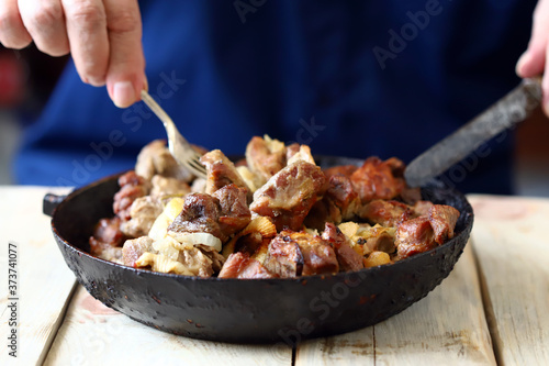 Selective focus. The chef mixes pieces of fried meat in a frying pan. Pork skewers in a skillet.