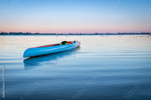 long and narrow racing stand up paddleboard floating on a calm lake in Colorado  morning recreation and fitness concept