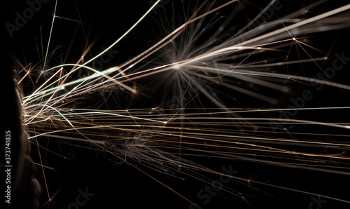 Sparks fly from lighter in dark environment with black background