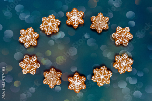 Christmas Ornament Pattern Frame made from homemade snowflakes shaped gingerbread. Top view, close-up on blue bokeh background
