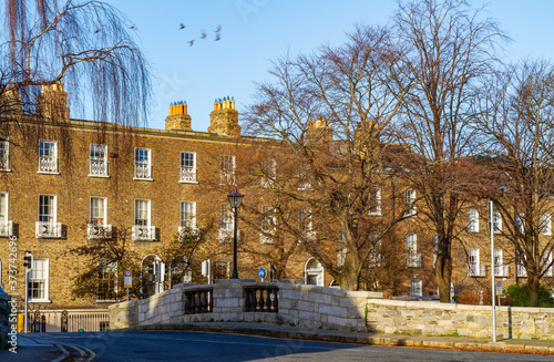 Huband Bridge at Grand Canal, Dublin, Ireland with Georgian Terrace streetscape, copper lantern, blue sky and winter trees. Canal lock bridge built in 1791 over Grand Canal, Georgian Dublin photo