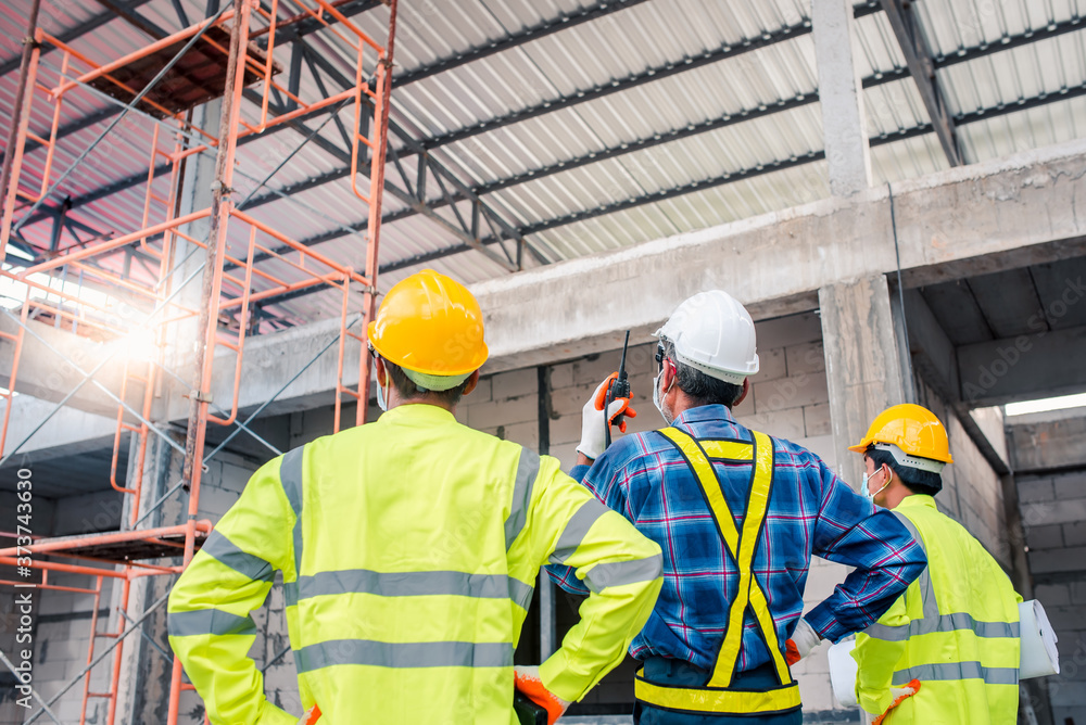 Engineers and construction workers wore a mask to prevent the Coronavirus (COVID-19) during construction using a construction site radio. Engineers and construction workers wore a mask to prevent the Coronavirus (COVID-19) during construction using a construction site radio.
