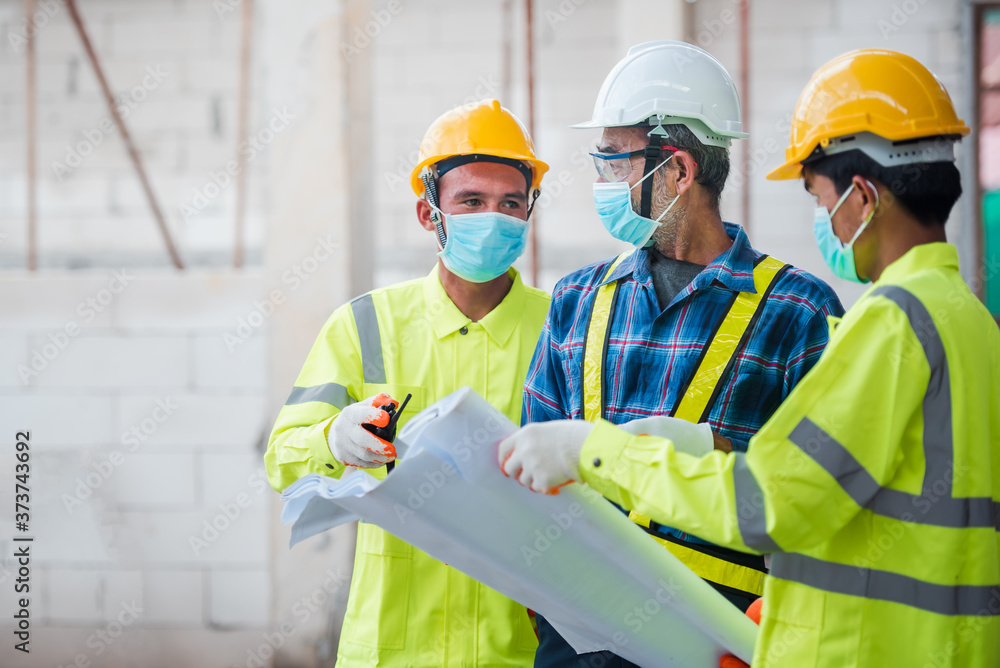 Engineers and construction workers put on a mask to protect against the Corona virus or Covid-19 during construction design work. Engineers and construction workers put on a mask to protect against the Corona virus or Covid-19 during construction design work.