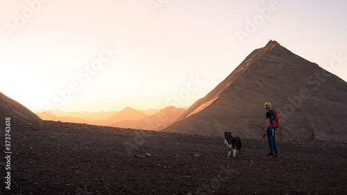 Hiker with dog at an idyllic sunrise in the Alps