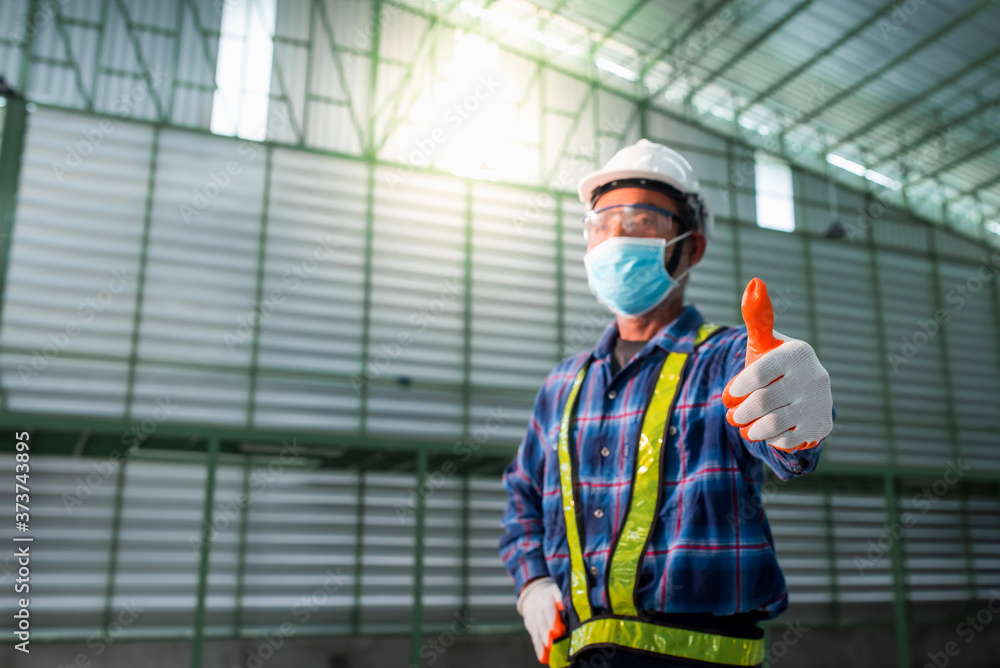 An elderly male engineer wears a mask to prevent the coronavirus (COVID-19) during work in a warehouse. An elderly male engineer wears a mask to prevent the coronavirus (COVID-19) during work in a warehouse.