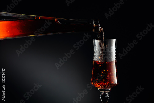 Aged golden fortified wine from the antique bottle being poured into a crystal glass.