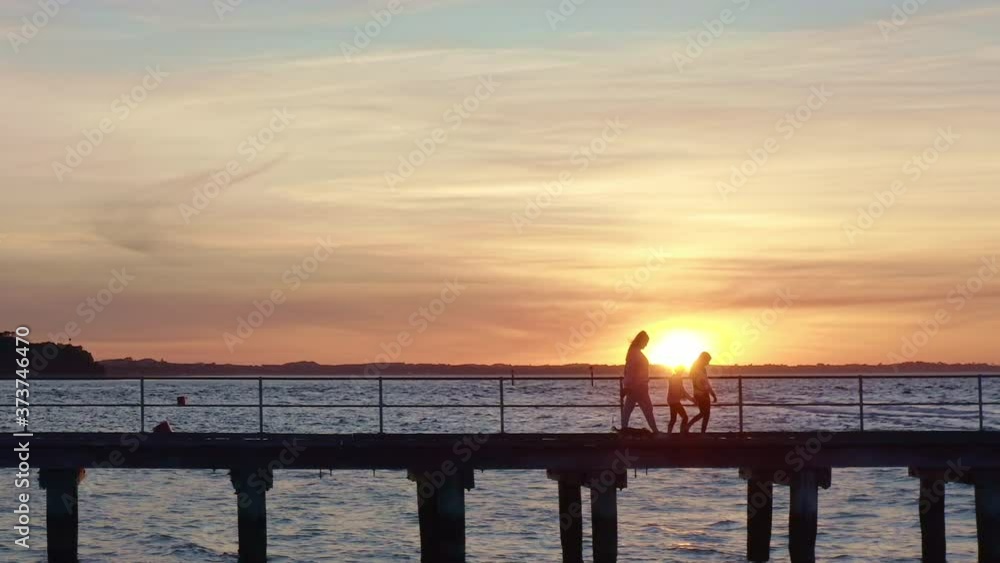 Family Walks On Pier at Sunset in Silhouette