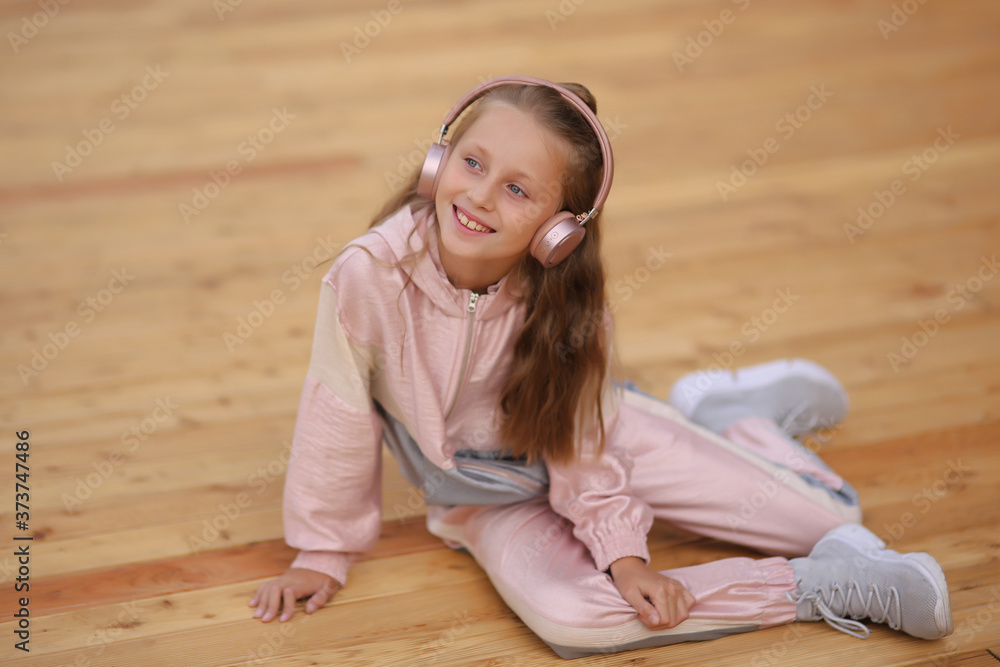 Naklejka premium Cheerful child in headphones. Autumn spring concept. street portrait of a girl. Child in the park