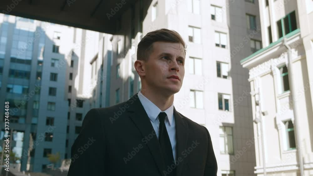 Portrait of Successful Businessman in Suit Walking Downtown on Streets of Business District. Confident business man goes to work in a modern office building. Portrait of Successful Businessman in Suit Walking Downtown on Streets of Business District. Confident business man goes to work in a modern office building.