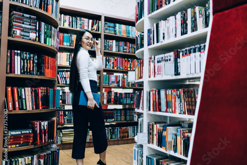 Young female with long hair standing in library