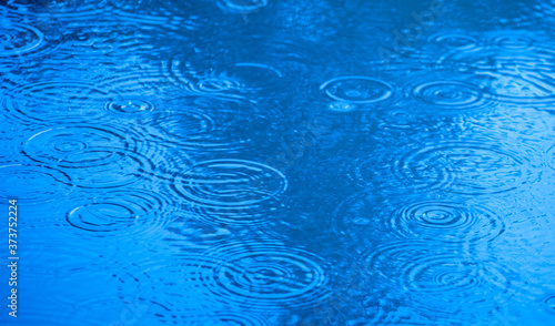 Sky reflection in water. Raindrops fall into a puddle.