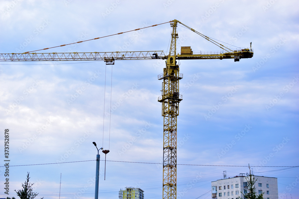 Tower construction crane on the background of the blue sky and the city Tower construction crane on the background of the blue sky and the city