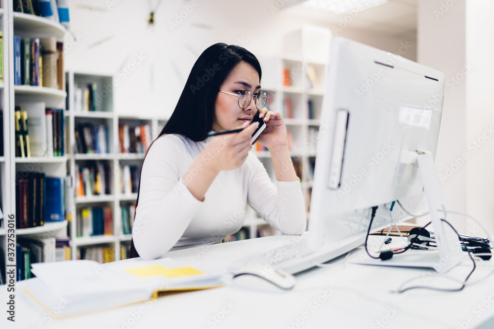 Asian female manager talking on smartphone in office Asian female manager talking on smartphone in office