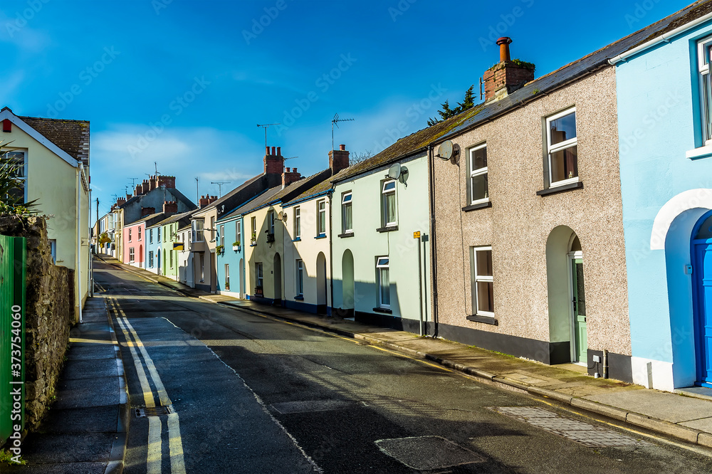 A view of multi-coloured houses in a typical street in Tenby, Pembrokeshire on a sunny day
