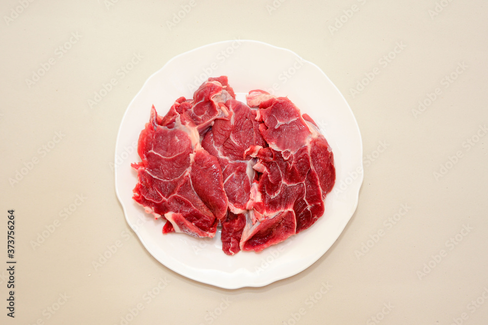 Raw beef meat steak on white plate on light background top view. Close up. Carnivore, keto Raw beef meat steak on white plate on light background top view. Close up. Carnivore, keto