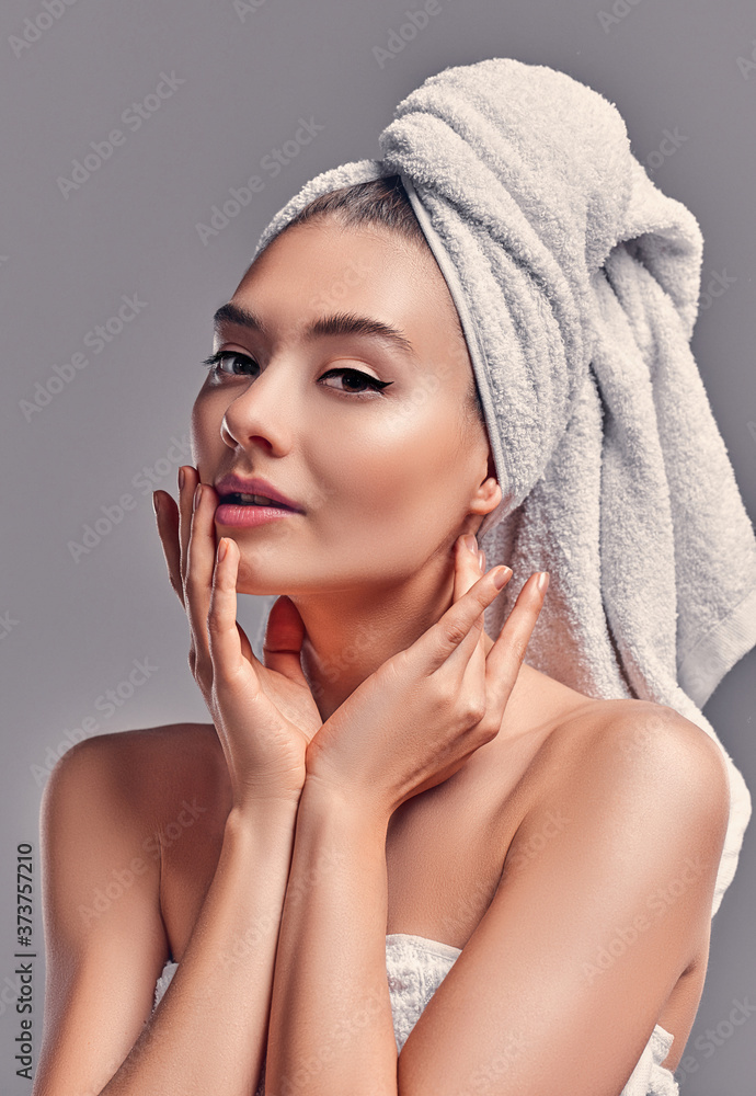 Cute attractive girl with towel on her head isolated on gray background. Skin care concept. Spa treatments, cosmetology, make-up. Cute attractive girl with towel on her head isolated on gray background. Skin care concept. Spa treatments, cosmetology, make-up.