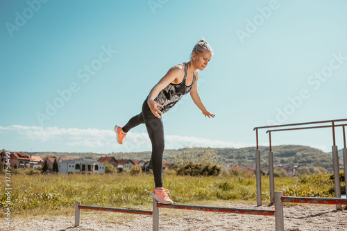 Young, blonde girl practicing in the park with metal bars. Balance exercise.