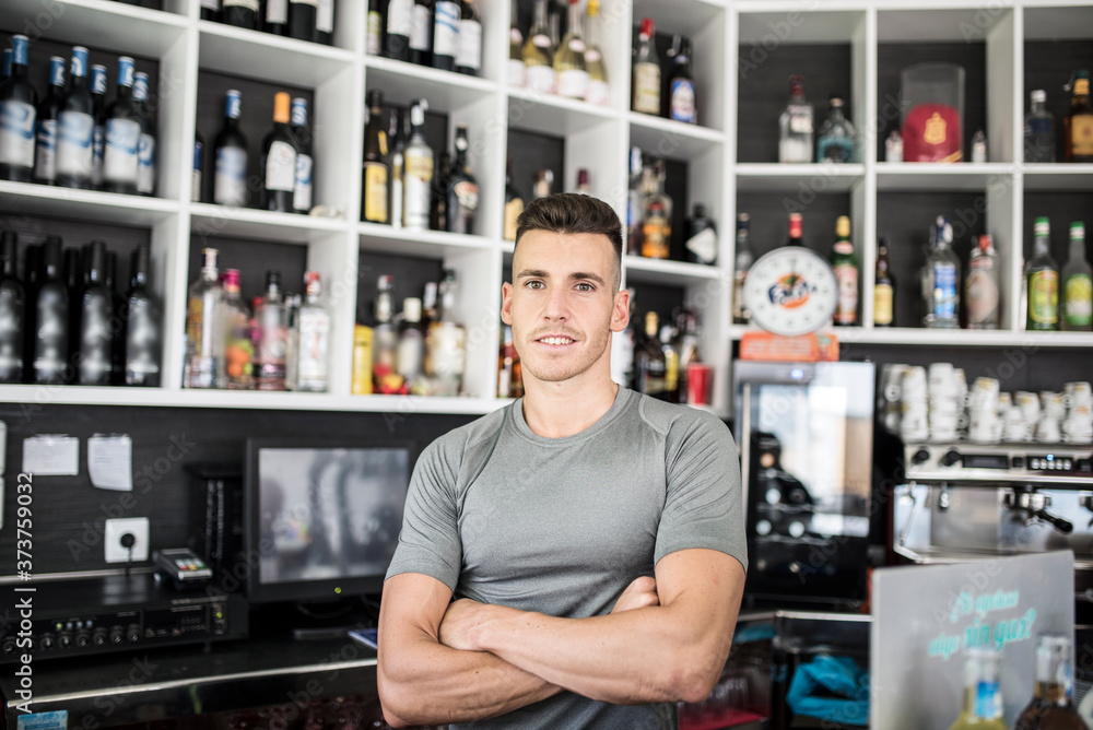 Young bar man posing in bar with bottle background