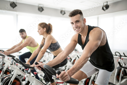 Fototapeta Group of people in spinning gym room