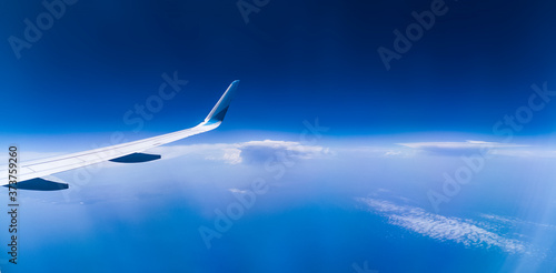 panorama über den wolken mit flugzeug flügel, tief blaue wolkenlandschaft mit blick auf den ozean und weit reichendem horizont 