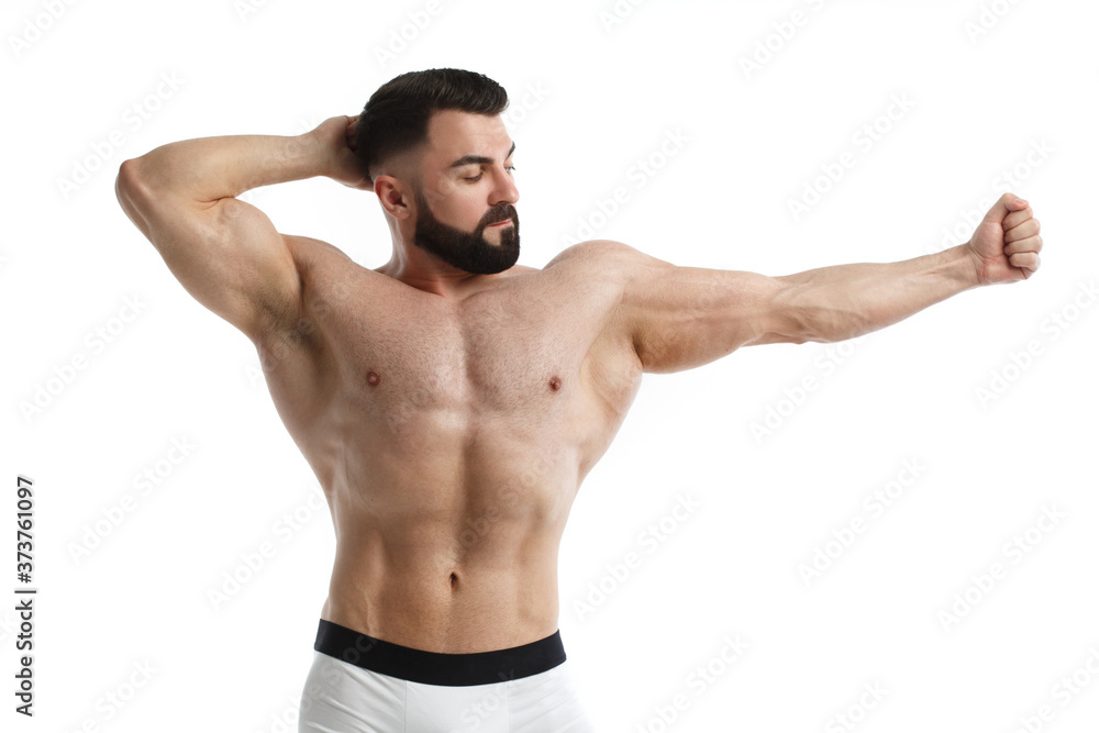 Athletic bearded man with a naked muscular torso holds one hand behind his head, the other extended to the side, isolated on white background.