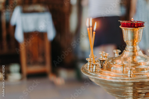 Christianity and Orthodoxy.Church. A blurred image of three burning candles in a temple in a Golden candlestick with a lamp on the background of the altar with a blurred background and space for text.