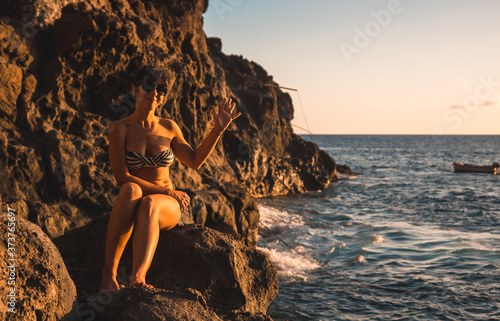 A young woman looking at the sea at sunset in the town of Poris de Candelaria on the nort-west coast of the island of La Palma, Canary Islands. Spain.