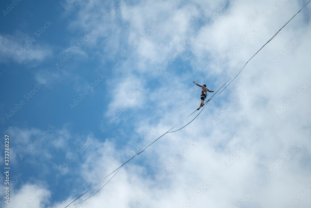 Highline slackline walking over valley with walking man with clouds on the background, Czech Republic Highline slackline walking over valley with walking man with clouds on the background, Czech Republic