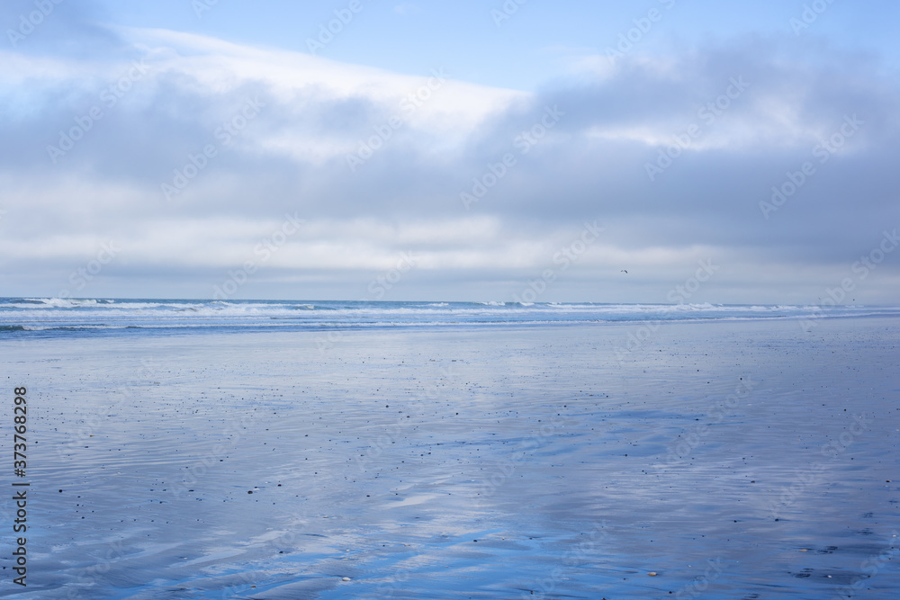 A wintery calm day at Waikuku Beach, Canterbury, New Zealand, with gentle waves, sand and a cloudy sky