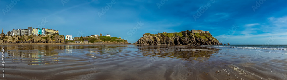 A panorama view of the South Beach, Castle Hill and Saint Catherine's Island in Tenby, Pembrokeshire at low tide on a sunny day
