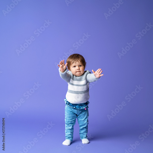 Full length excited baby, takes the first step on a purple background.