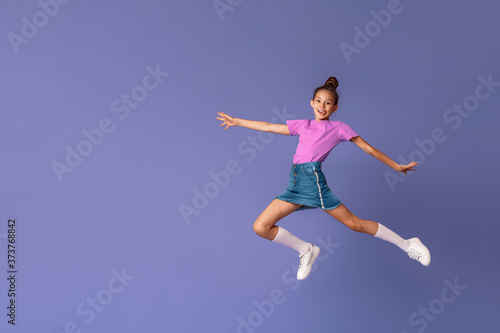 happy fashionable girl jumps in air in full height, on purple background.