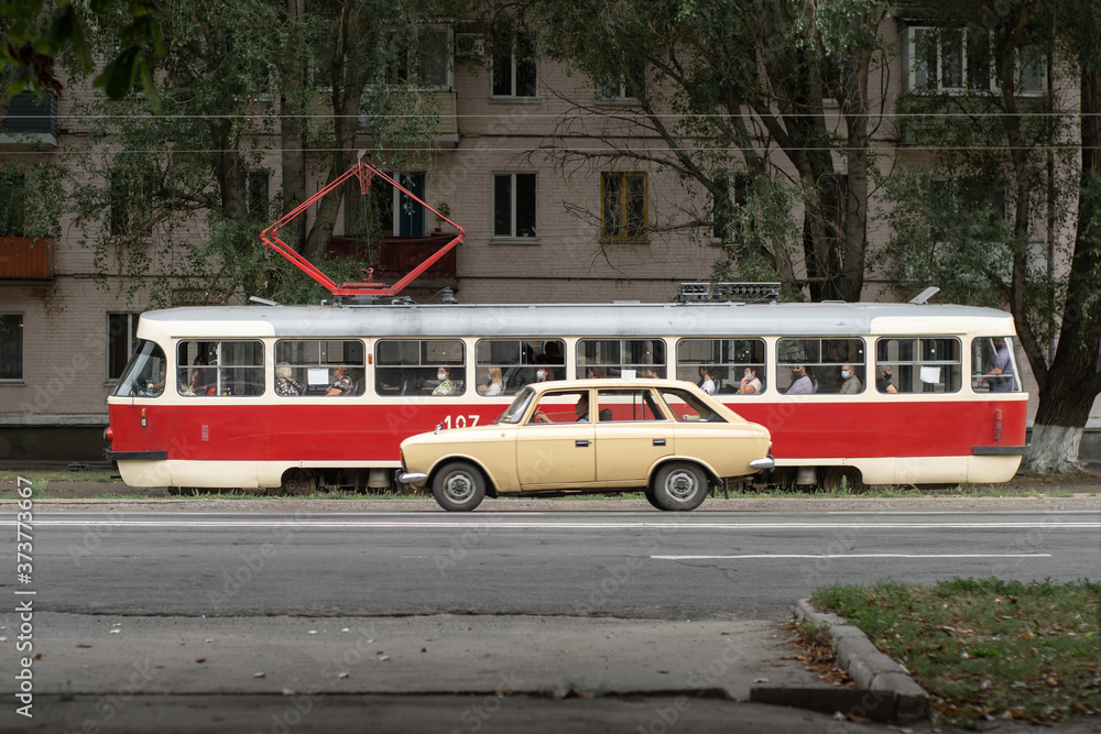 Konotop, Sumy Oblast, Ukraine - 24 August, 2020: Old Soviet Tatra tram and car on the road, side view. Transport of the Soviet Union.