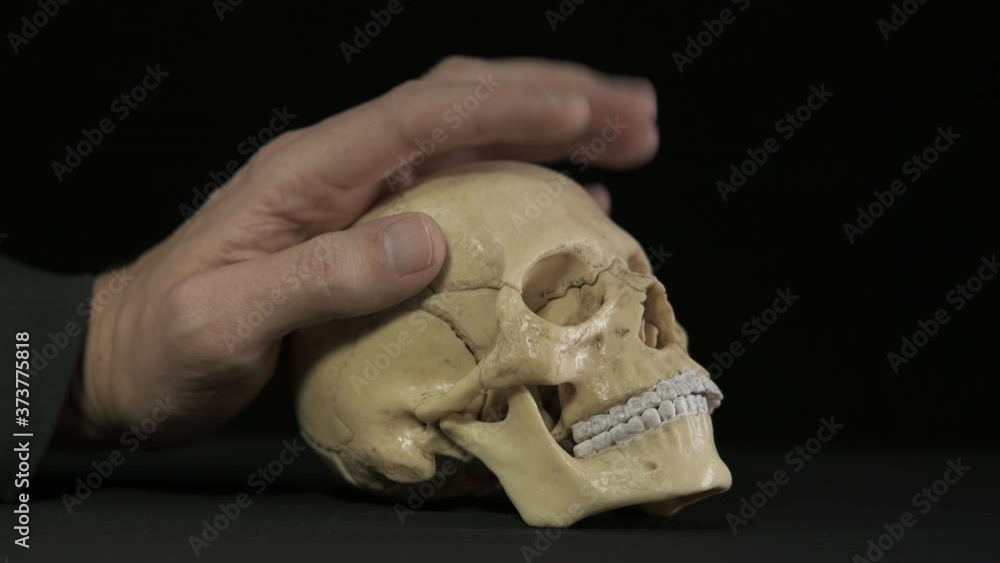 Think with a skull. A man strokes a human skull. Think with a skull. A man strokes a human skull.