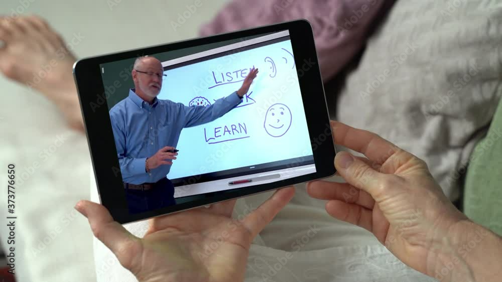 Online teacher communicating with girl school student by webcam conference call. Internet tutor teaching remote learning class. E learning from home concept. Over shoulder close up tablet screen view. Online teacher communicating with girl school student by webcam conference call. Internet tutor teaching remote learning class. E learning from home concept. Over shoulder close up tablet screen view.