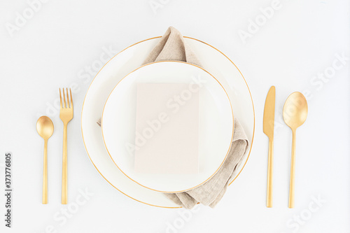 Festive christmas, wedding, birthday table setting with golden cutlery and porcelain plate