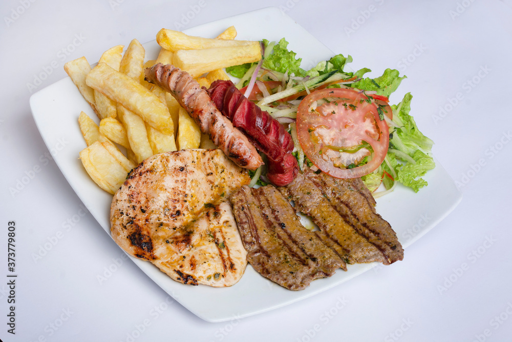 Pollo, carne y chorizo asado con papas fritas y vegetales