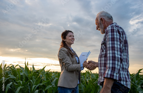 Farmer and business woman shaking hands in field photo