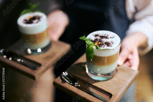 barista holding two mugs of decorated flaky coffee photo