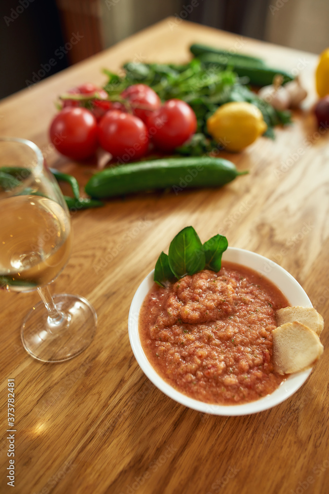 Close up of bowl of tomato soup or Pappa al Pomodoro served with a glass of white wine. The soup with tomatoes and bread, traditional Italian Tuscan dish Close up of bowl of tomato soup or Pappa al Pomodoro served with a glass of white wine. The soup with tomatoes and bread, traditional Italian Tuscan dish
