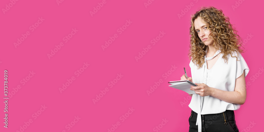 Charming woman makes entries in the diary and looks into the camera Charming woman makes entries in the diary and looks into the camera