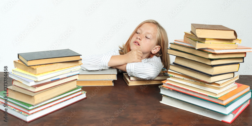 Portrait of a teenage girl who sits at a table among the books and looks to the side. Isolated background. Portrait of a teenage girl who sits at a table among the books and looks to the side. Isolated background.