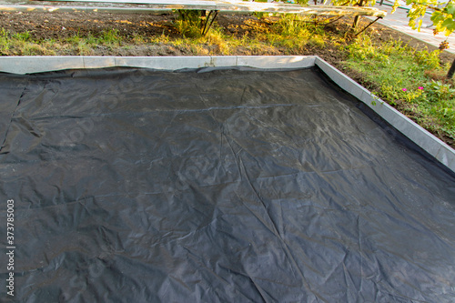 The base for tiling is prepared using a membrane that suppresses the growth of weeds and prevents mixing of rubble and earth. Selective focus. photo