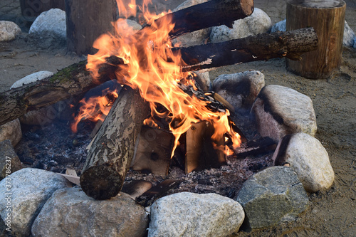 A burning fire of wood, lined with round stones.