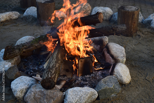 A burning fire of wood, lined with round stones.
