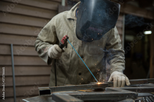 welder welds metal with an electric welding machine. metal works in the workshop close up. 