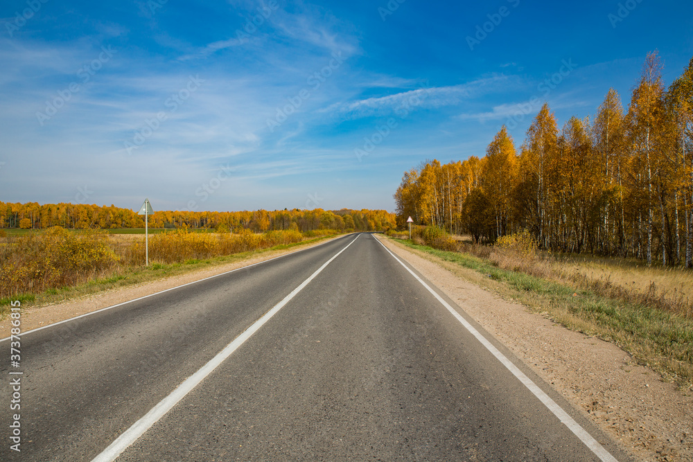 Highway, road and autumn trees with blue sky. Beautiful autumn natural landscape Highway, road and autumn trees with blue sky. Beautiful autumn natural landscape