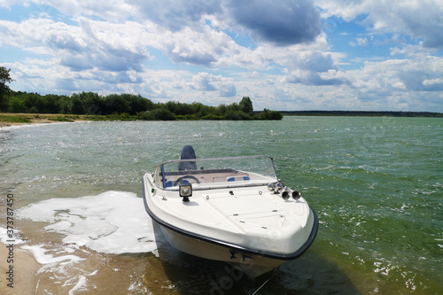 Fototapeta Naklejka Na Ścianę i Meble -  White motor boat motorboat stands near the shore of the lake