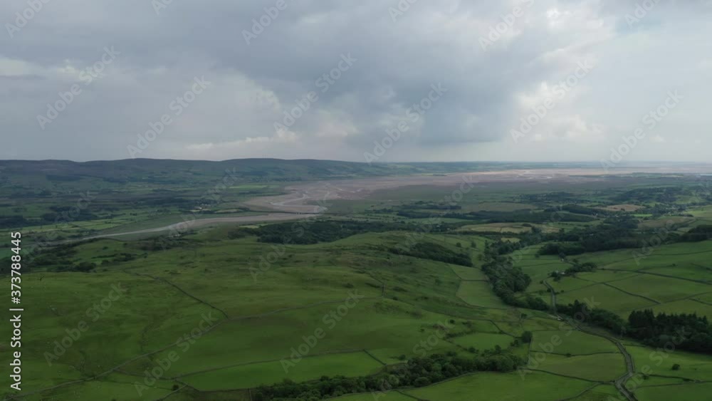 Aerial backwards shot of the rich green landscape around a coastal bay in the English Lake District. Aerial backwards shot of the rich green landscape around a coastal bay in the English Lake District.