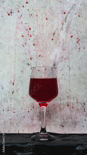 red wine splashing in a wine glass, with a white wooden texture in background.